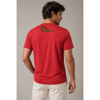 Man wearing a red t-shirt with a logo on the back against a neutral background