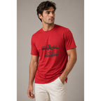 Man wearing a red t-shirt with a graphic design on a neutral background